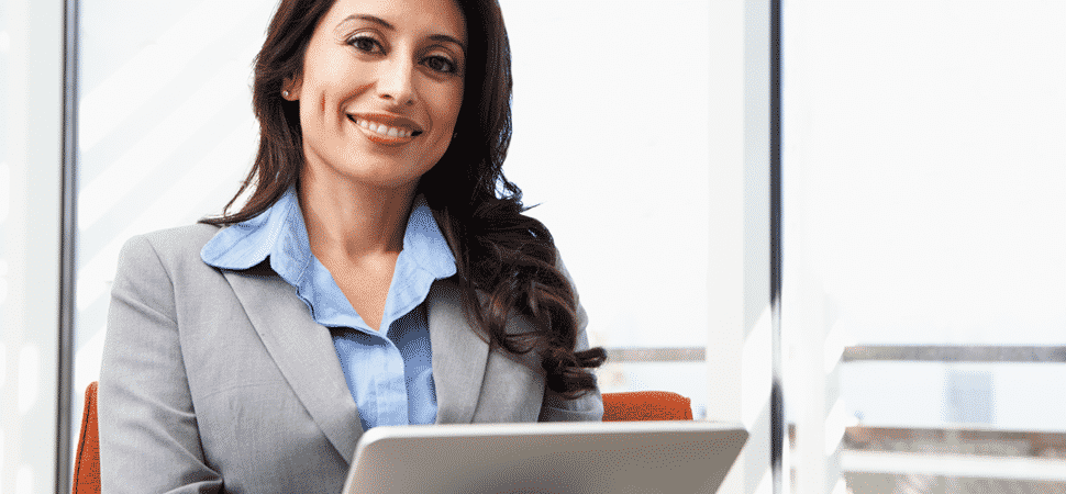 Business woman working on laptop smiling at camera
